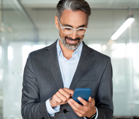  A businessman in a suit is looking at his phone.