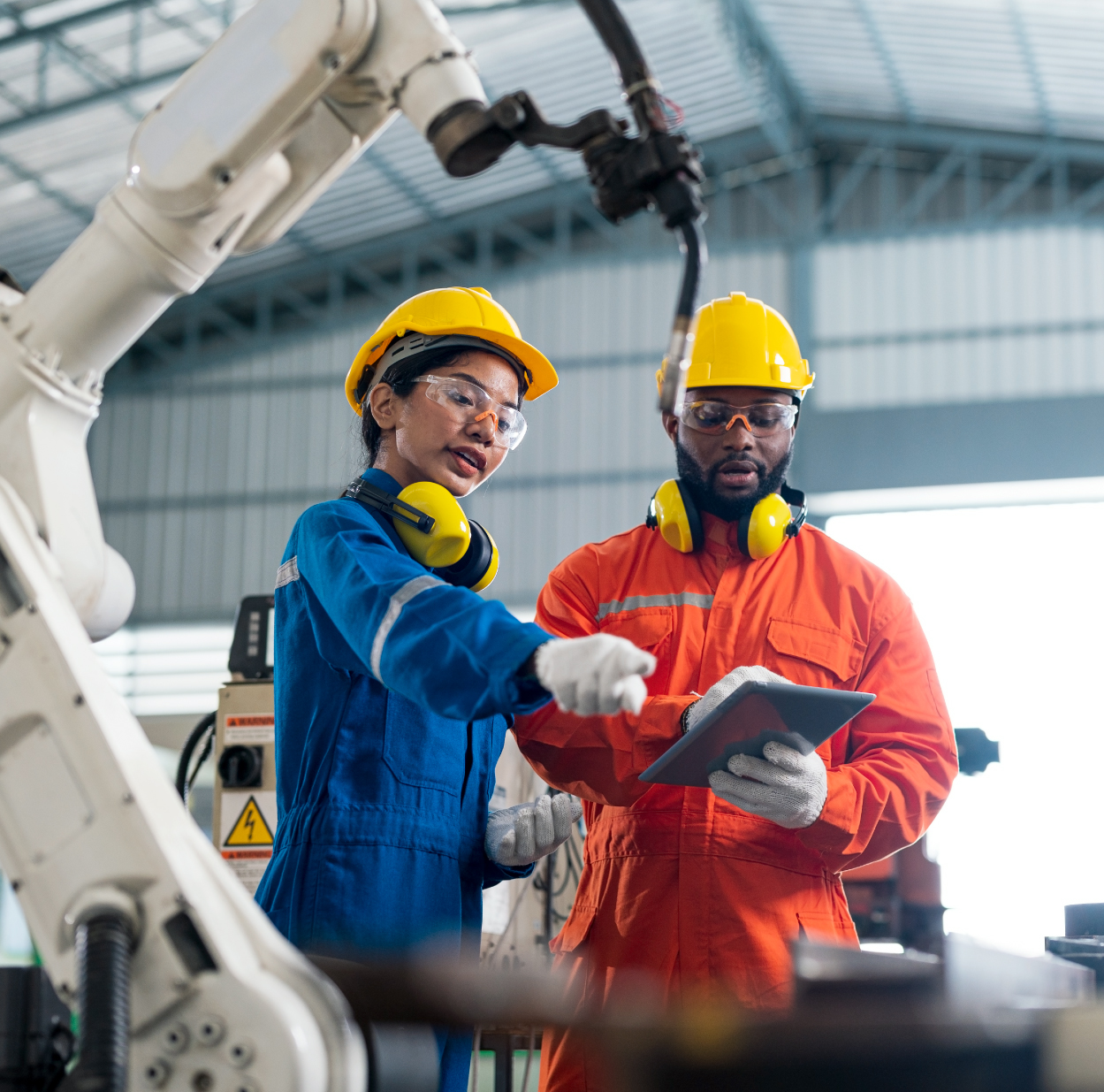 Manufacturers in hard hats consulting on shop floor