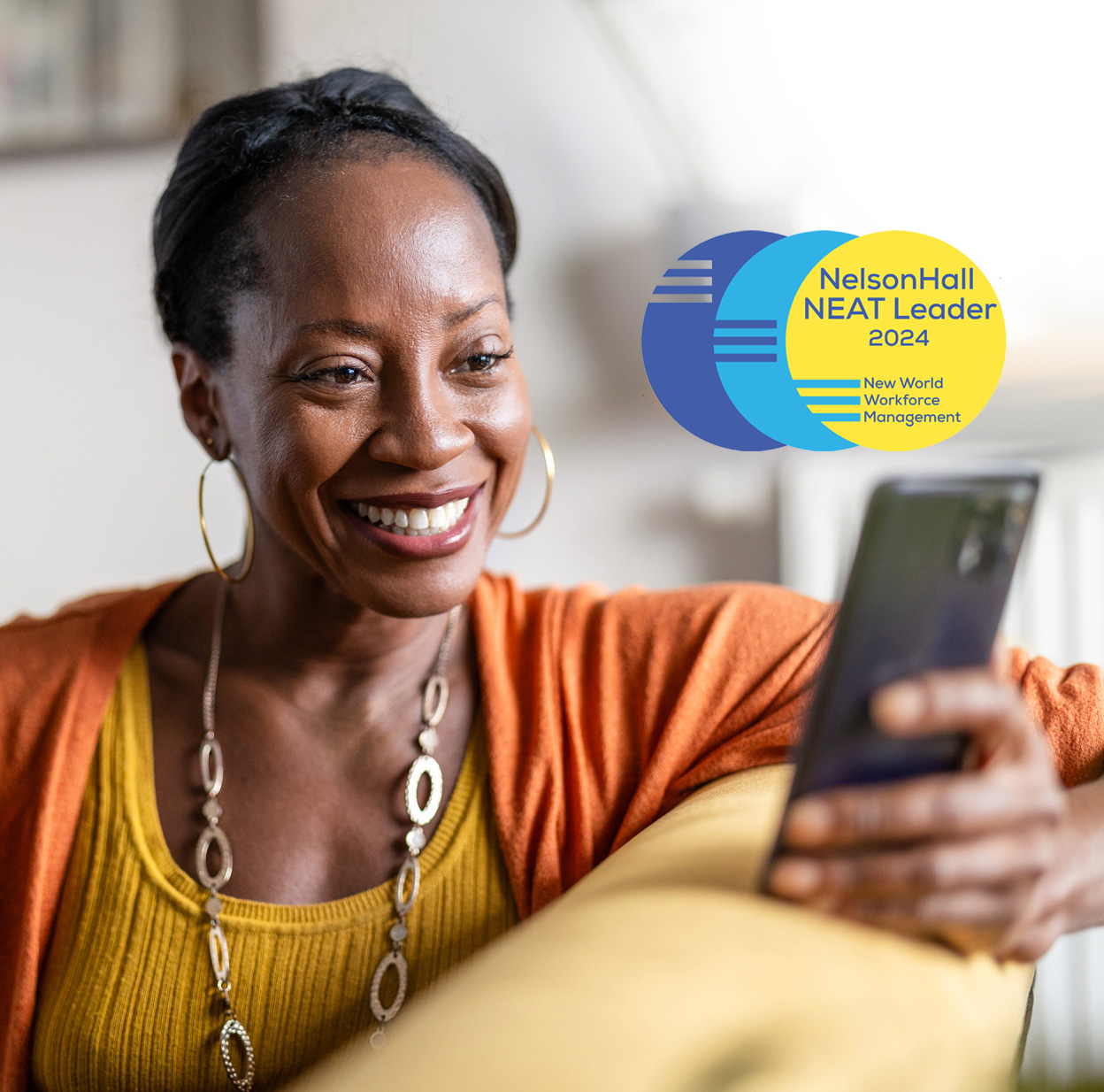  A smiling woman wearing an orange shirt is looking at her phone.