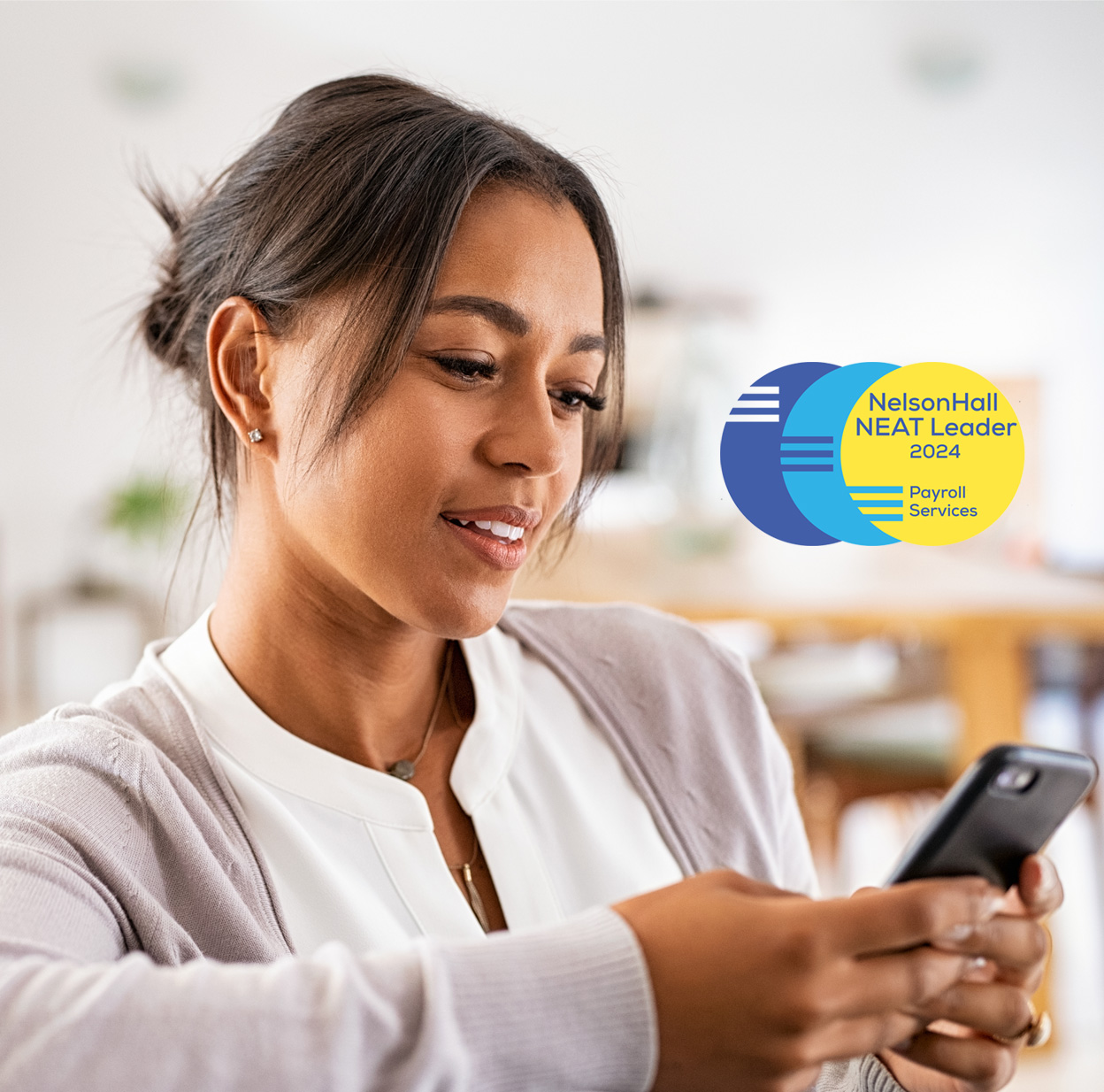 Smiling woman wearing a tan sweater looking at her phone.