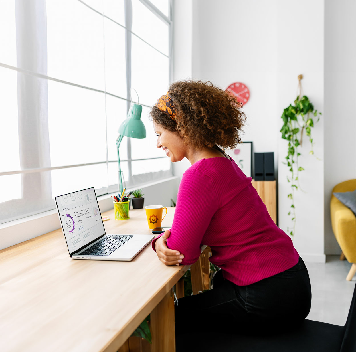 Woman sitting at desk in front of a laptop smiling