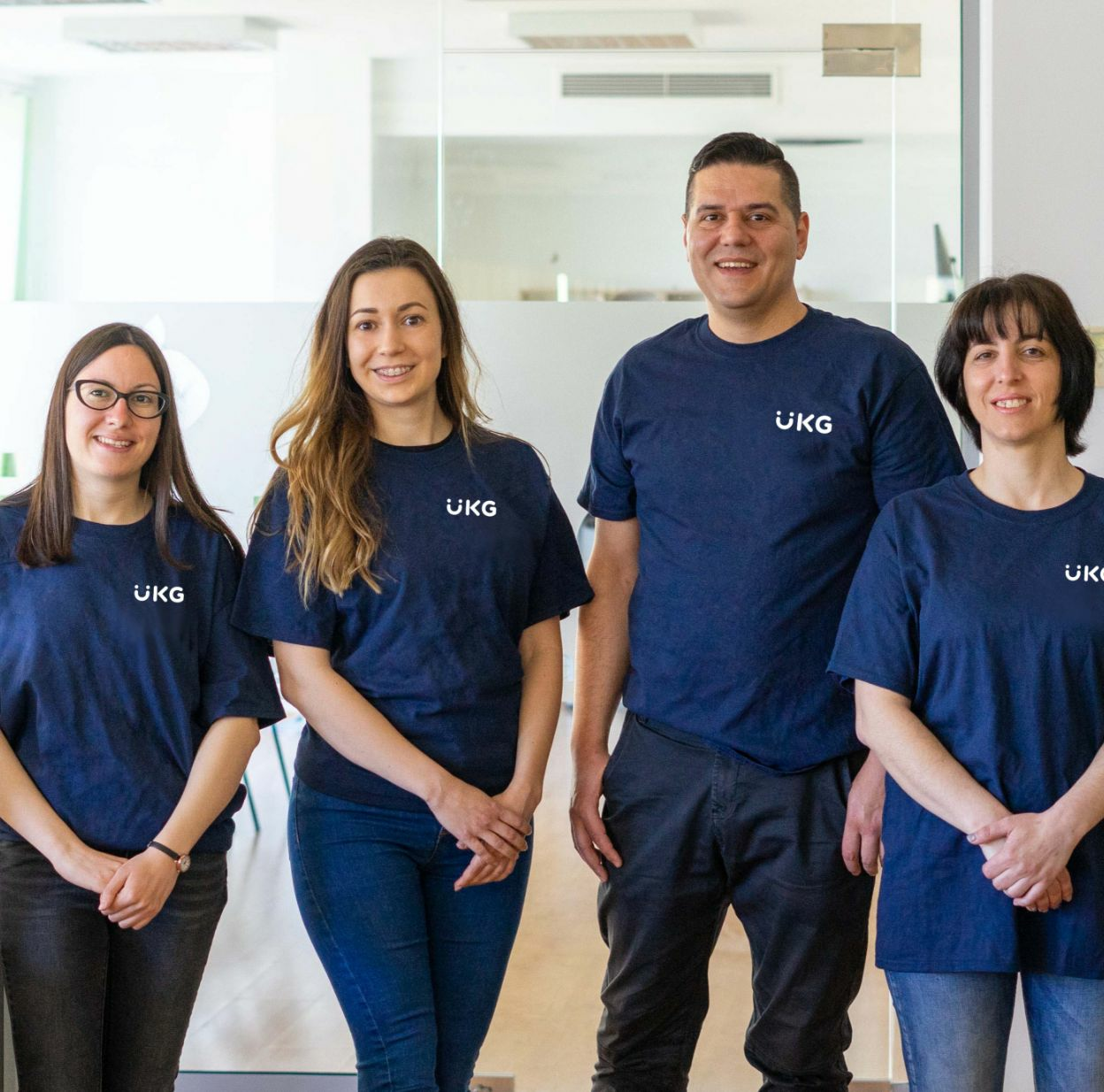 A group of four people wearing blue shirts with the text "UKG" on them.