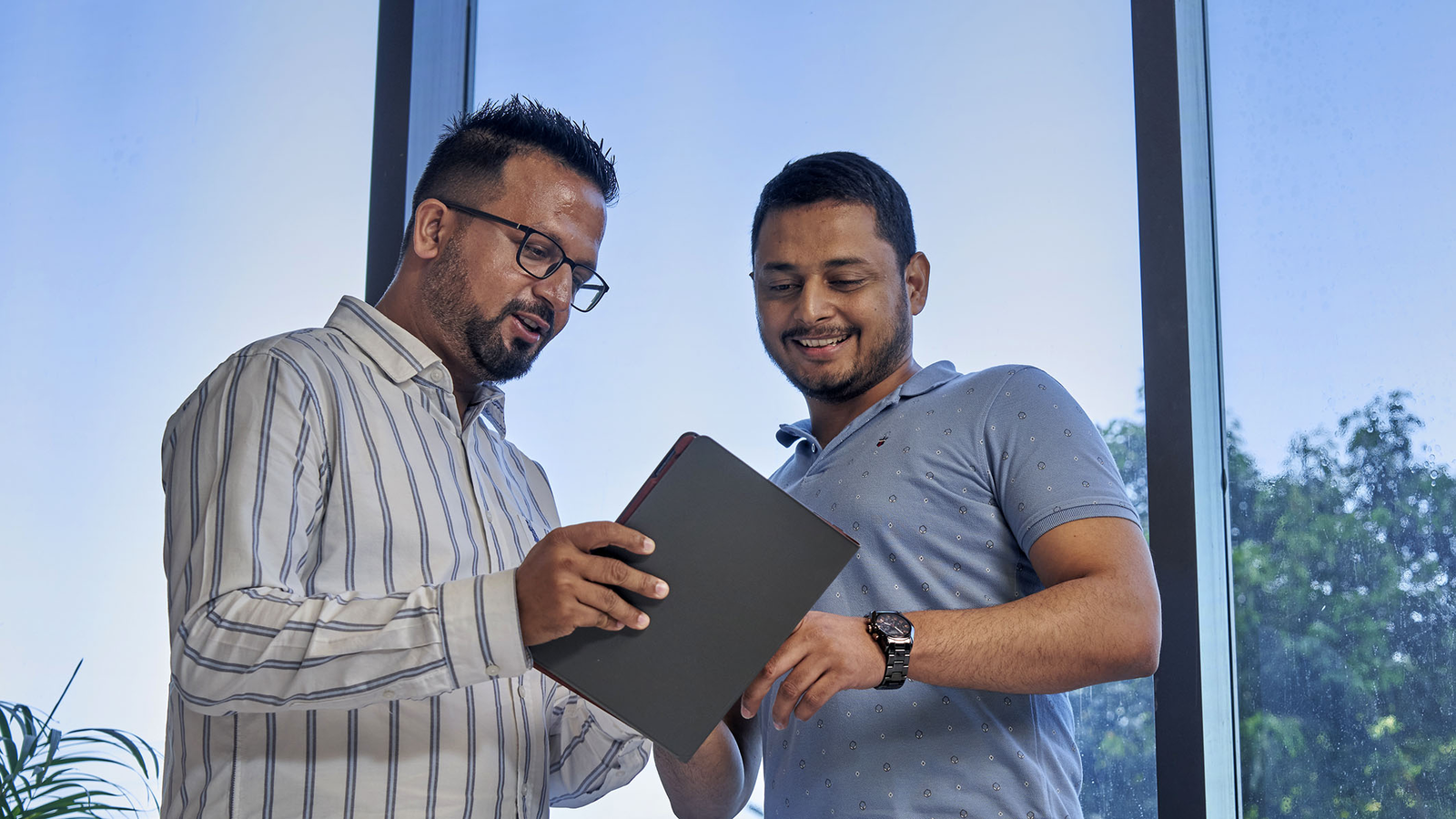  Two men are looking at a tablet together.