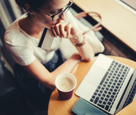 A women looking at her laptop with a credit card in her hand and coffee on the table