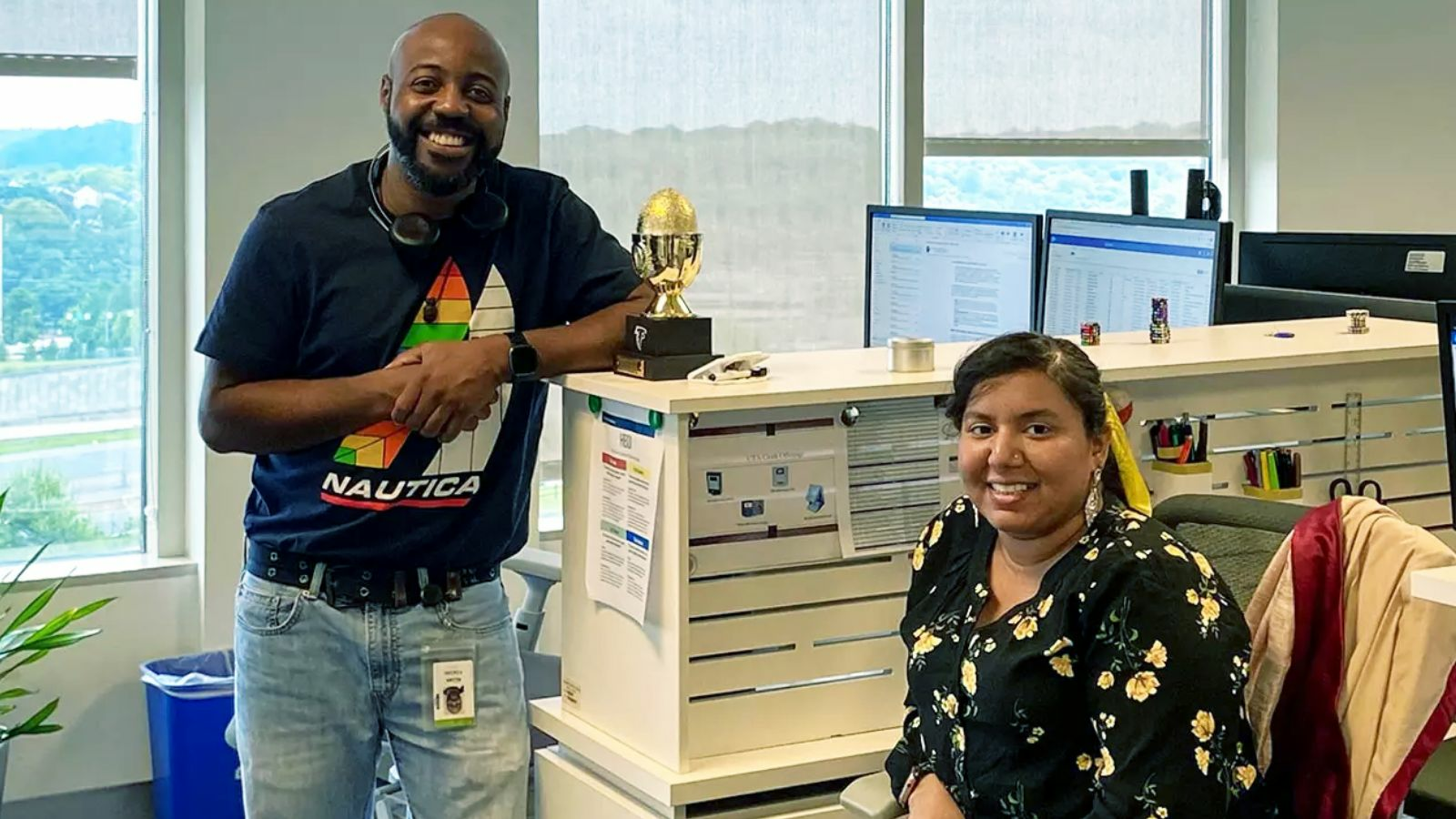 A smiling man and woman pose for a photo in an office setting.