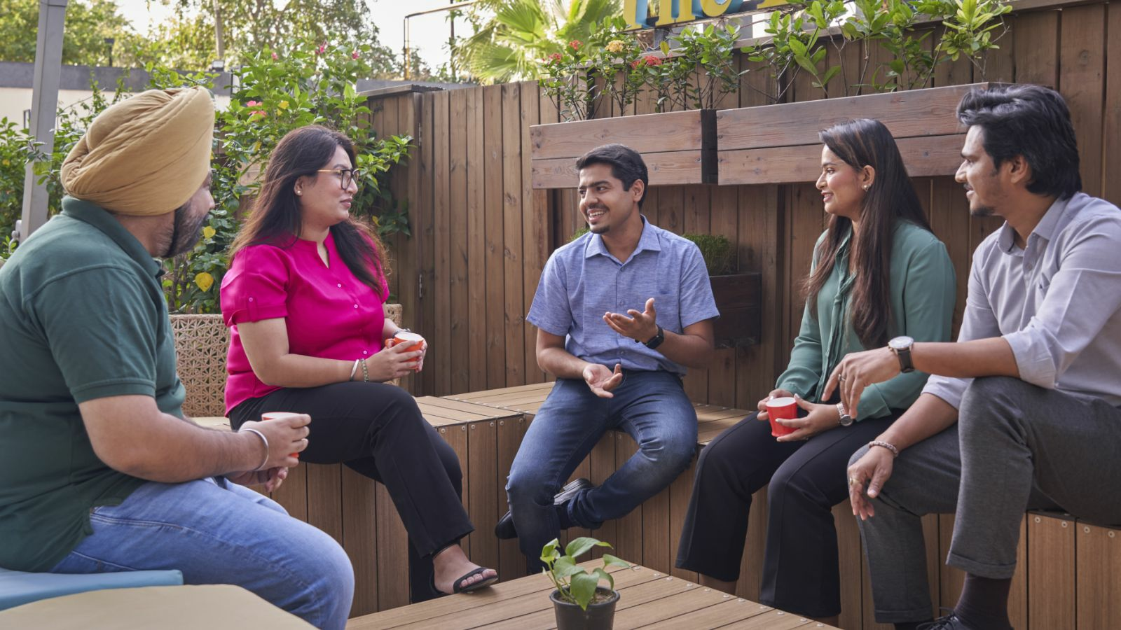  A group of four people are sitting on a bench and talking.