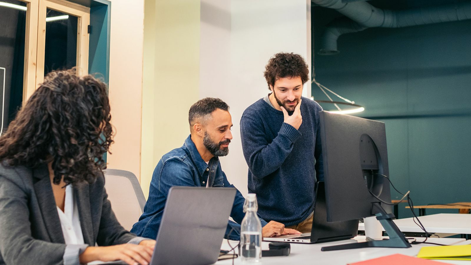 Three business people are working together in an office space.