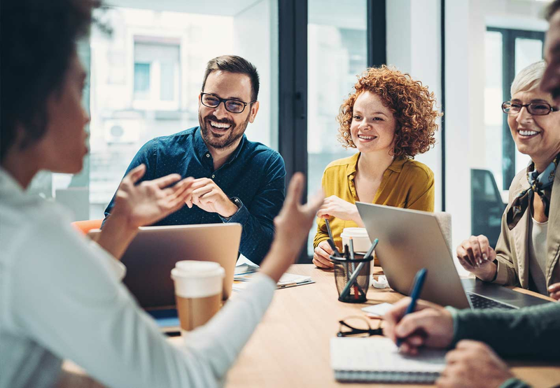 A group of four business professionals are sitting around a table having a meeting.