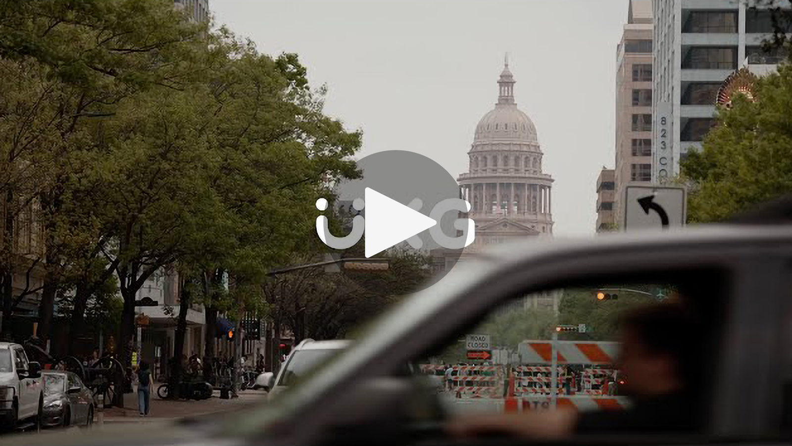 A view of the Texas State Capitol building from inside a car on a busy street.