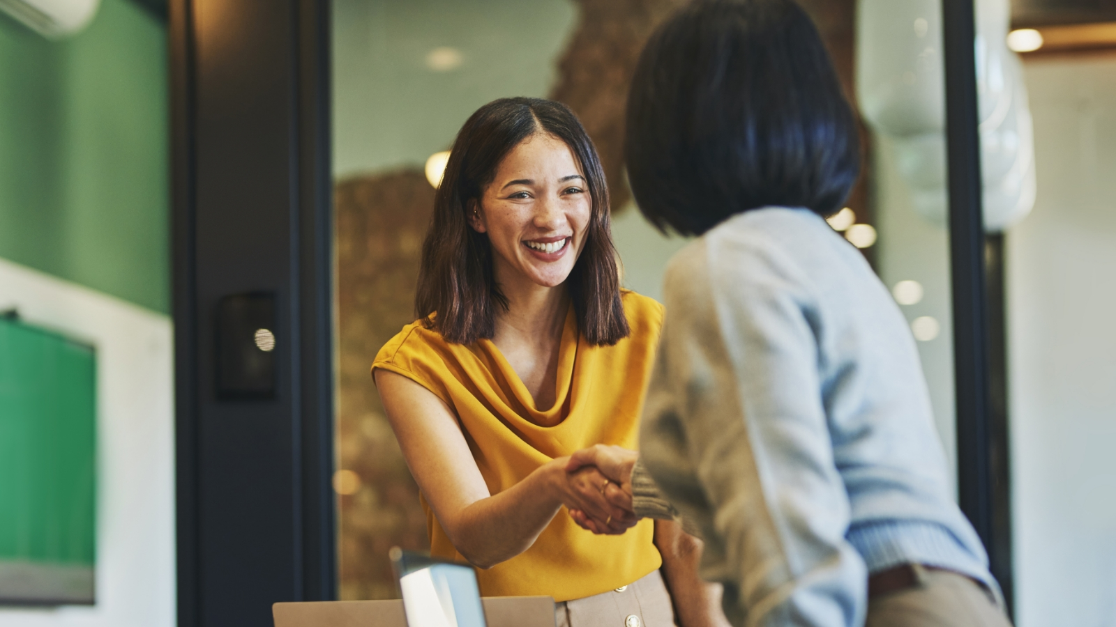 Two businesswomen shaking hands in an office.