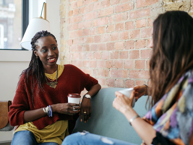 two women talking and drinking coffee