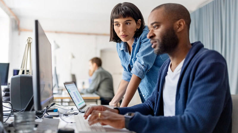 a man and a women looking at a computer together