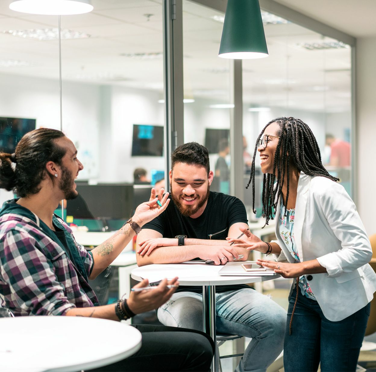 Three business professionals are sitting around a table having a casual meeting.